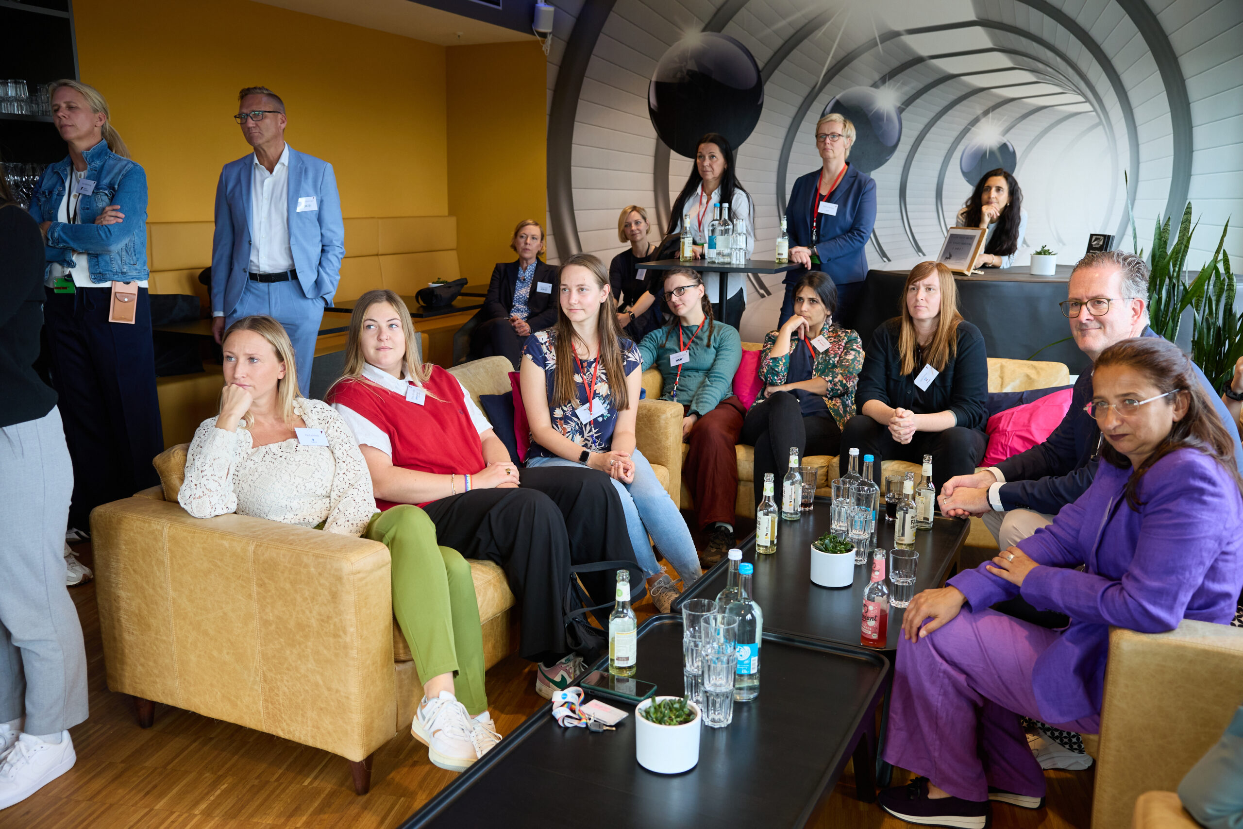 Teilnehmende einer After-Work-Veranstaltung diskutieren in einer modernen Lounge über Gender Audit und Unternehmensvielfalt