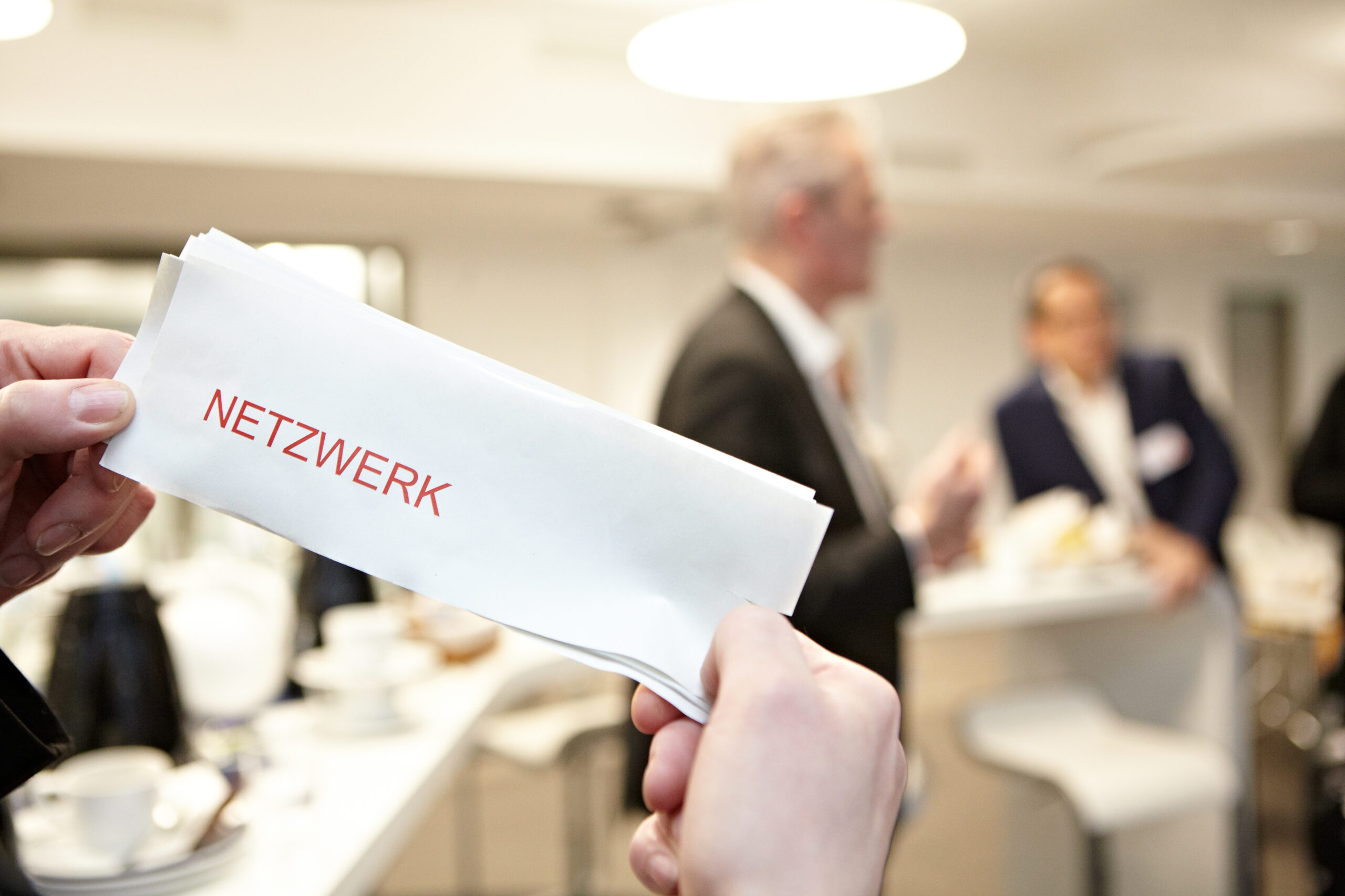 Person hält Schild mit Aufschrift Netzwerk bei einem Business-Netzwerktreffen, Fokus auf Networking.