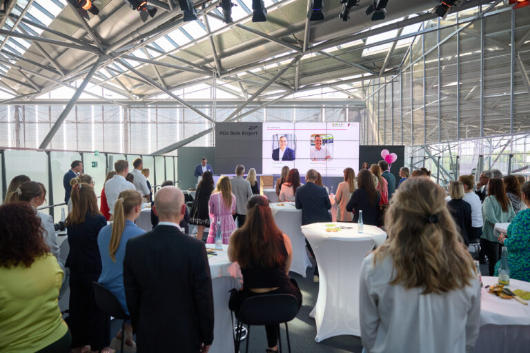 Menschen bei einem Leadership-Event am Köln Bonn Airport – Vortrag vor einer diversen Gruppe in moderner Umgebung.